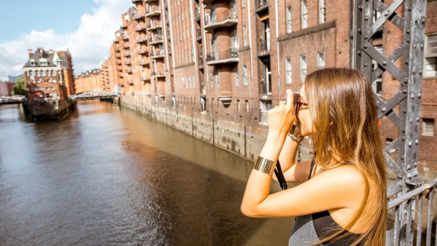 Woman taking a picture of the Speicherstadt district, a UNECSCO World Heritage site in Hamburg, Germany